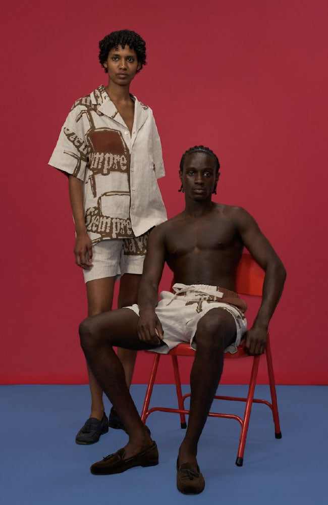 Two men pose against red and blue background wearing Studio Afuera minimalist linen separates with organic, artistic prints